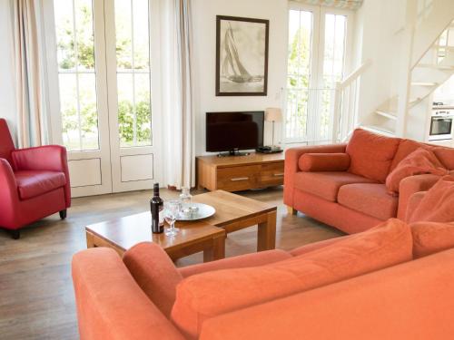 ノールトウェイケルハウトにあるHoliday Home Bungalowparck Tulp & Zee by Interhomeのリビングルーム(オレンジ色のソファ2台、テレビ付)