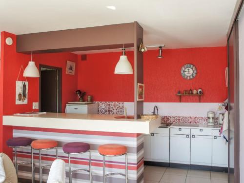 - une cuisine avec des murs rouges et des tabourets de bar dans l'établissement Holiday Home Gevanac by Interhome, à Crozon