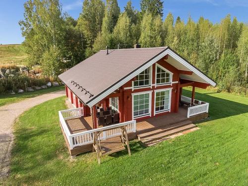 une petite maison rouge avec une grande terrasse sur une pelouse dans l'établissement Holiday Home Myllymökki by Interhome, à Hara