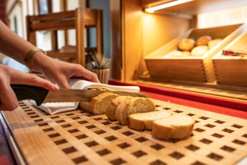 a person cutting bread on a cutting board with a knife at Bundt's Hotel & Gartenrestaurant in Hamburg