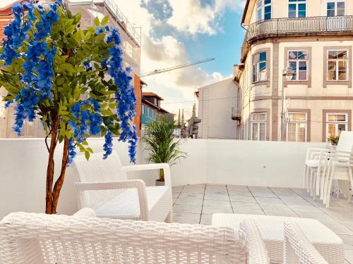 a patio with white chairs and a tree with blue flowers at The Arch - Charming Apartments in the Historic Center in Braga