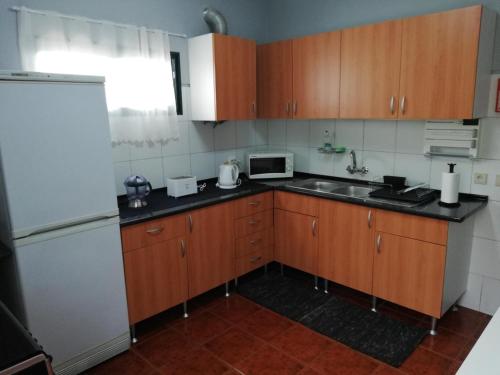 a kitchen with wooden cabinets and a sink and a refrigerator at House Joel & Sonia with sea view in Funchal