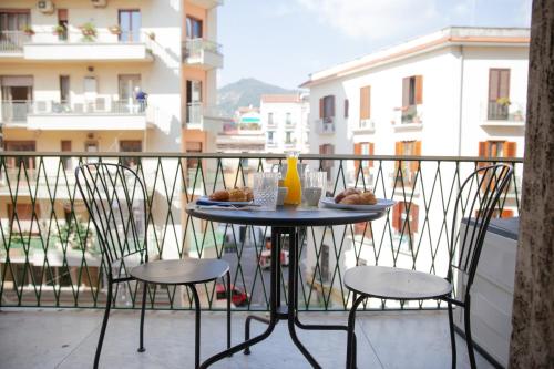 einen Tisch und Stühle auf einem Balkon mit Essen drauf in der Unterkunft Appartamento Velia in Salerno