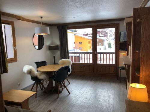 ein Wohnzimmer mit einem Tisch und Stühlen sowie einem Balkon in der Unterkunft Studio Chalets de Solaise in Val dʼIsère