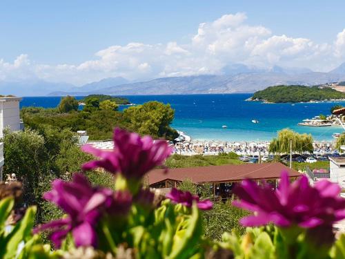 a view of a beach with purple flowers in the foreground at Hotel Mira Mare in Ksamil