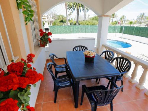 a blue table and chairs on a balcony with red flowers at Holiday Home Vicky by Interhome in Riumar