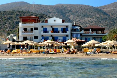 a group of people sitting on a beach with umbrellas at Vlachakis Hotel in Stalís