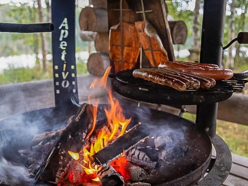 deux saucisses cuisinant sur un grill avec des flammes dans l'établissement Holiday Home Tuomaantupa by Interhome, à Hara