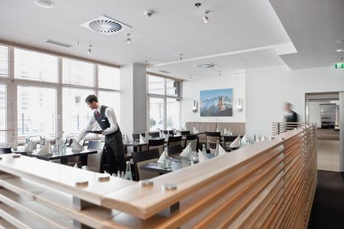 Un hombre de pie en un comedor con mesas. en Holiday Inn Munich City Centre by IHG, en Múnich