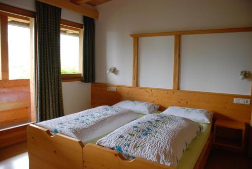 two beds in a room with two windows at Aria d'Bosch in Badia