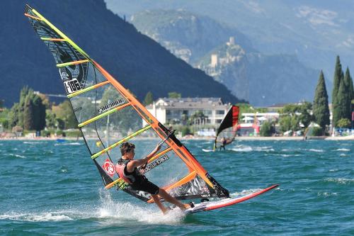a man is windsurfing on the water with a sail at HOODY ACTIVE & HAPPINESS HOTEL in Arco