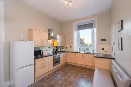 The Polwarth Apartment في إدنبرة: مطبخ مع ثلاجة بيضاء ونافذة