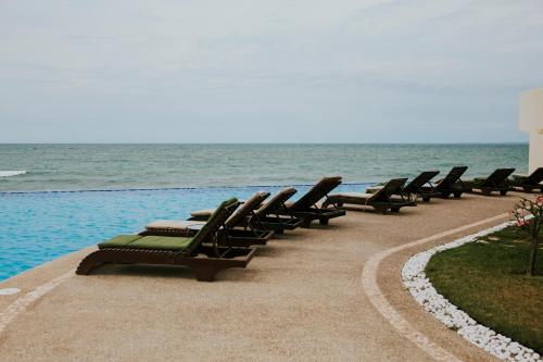 a row of lounge chairs sitting next to the ocean at Diamond Bay in Mazatlán