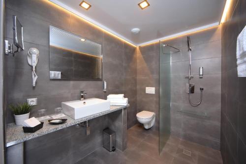 a bathroom with a sink and a shower and a toilet at Hotel Central 1920 in Špindlerův Mlýn