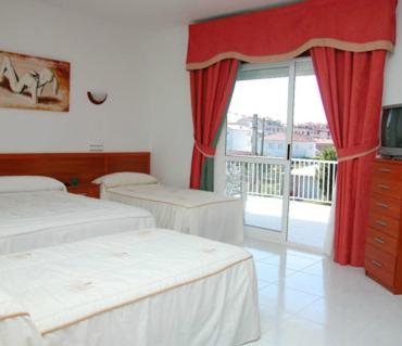 a bedroom with two beds and a window with a balcony at Hotel Ria Toxa in Revolta