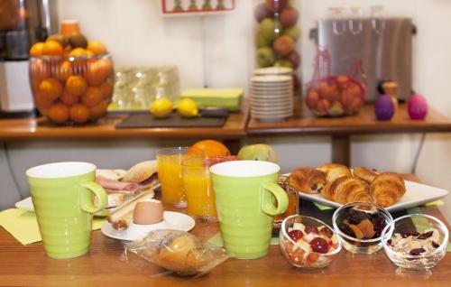 a table with cups and plates of food and fruit at ibis Styles Le Puy en Velay in Le Puy en Velay