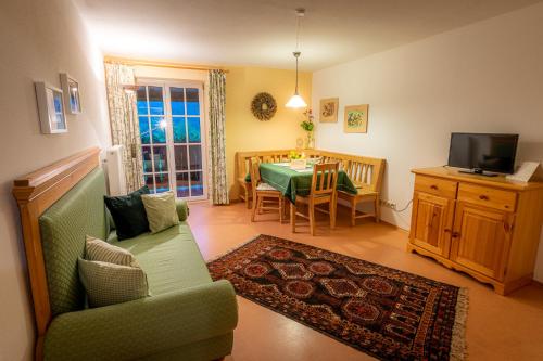a living room with a green couch and a table at Ferienwohnungen Hotel Garni Dörflerwirt in Aflenz Kurort