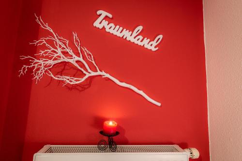 a red wall with a tree branch and a candle at Ferienwohnungen Hotel Garni Dörflerwirt in Aflenz Kurort