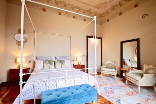 ein Schlafzimmer mit einem weißen Himmelbett und einem Stuhl in der Unterkunft Villa Farinelli in Cadegliano Viconago