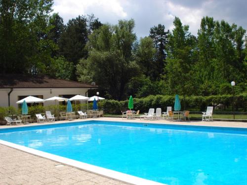 a large blue swimming pool with chairs and umbrellas at Rio Verde camping villaggio in Costacciaro