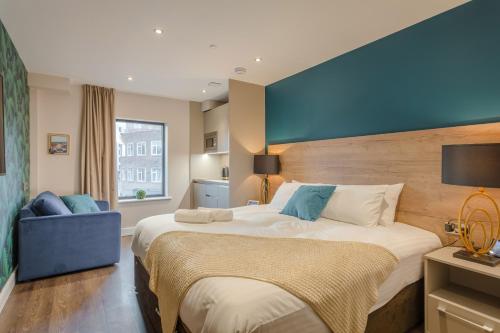 a bedroom with a large bed and a blue wall at Dwell City Living in Nottingham