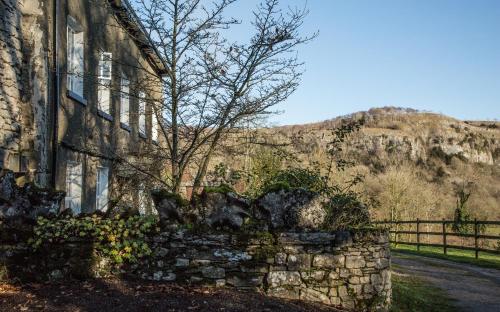 an old stone house with a stone wall next to a road at Witherslack Hall Farmhouse in Grange Over Sands