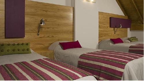 a hotel room with two beds and purple lamps at Hosteria ACA al Sur in Villa La Angostura