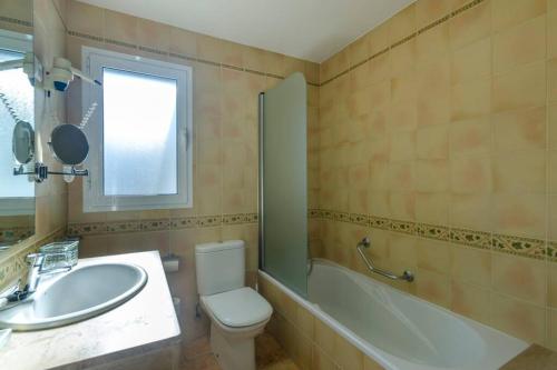 a bathroom with a sink and a toilet and a bath tub at Apartamento Addaia in Port d'Addaia