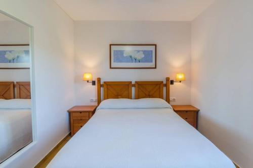 a bedroom with a white bed and a mirror at Apartamento Addaia in Port d'Addaia