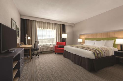 a hotel room with a bed and a desk and a television at Country Inn & Suites by Radisson, Lubbock Southwest, TX in Lubbock