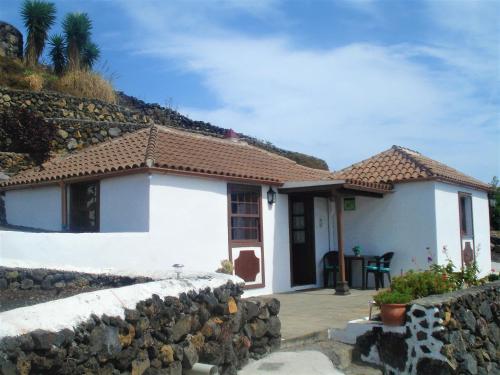 een klein wit huis met een stenen muur bij Casa Los Volcanes in Tigalate