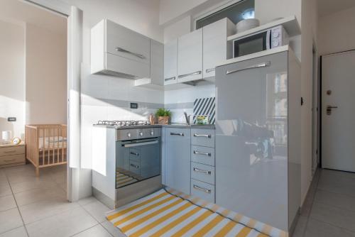 a kitchen with white cabinets and a blue stove top oven at Babyaccommodation Family Experience in Pietra Ligure
