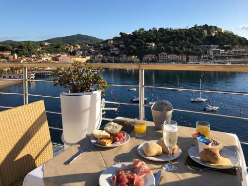 a table with plates of food and a view of the water at Hotel Plaza in Porto Azzurro