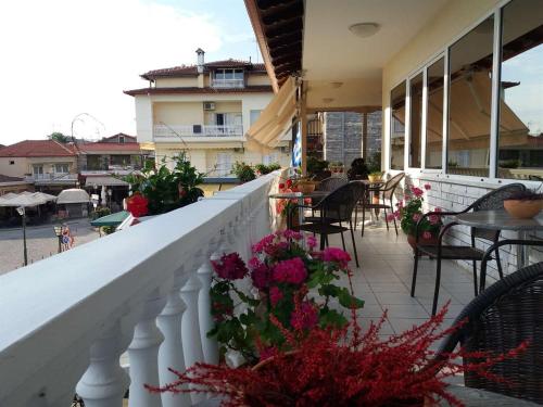 a balcony with tables and chairs and flowers at Olympus View Rooms Sauna & Spa in Litochoro