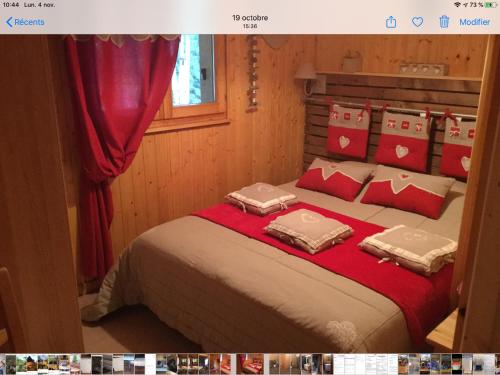 a bedroom with a large bed with red and white pillows at Chalet le val’tin in Ventron