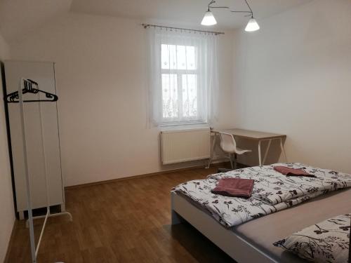 1 dormitorio con cama, escritorio y ventana en Ubytování v podkroví, en Jeseník