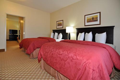 two beds in a hotel room with red covers at Country Inn & Suites by Radisson, Conway, AR in Conway