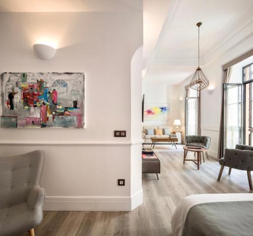 a white room with a bed and a living room at Puerta Catedral Holiday Suites in Seville