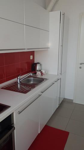 eine weiße Küche mit einem Waschbecken und einer roten Wand in der Unterkunft Penthouse HEART OF SLAVONIA **** in Ðakovo