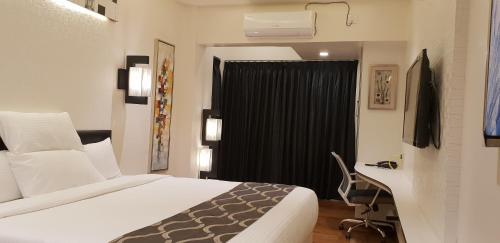 a bedroom with a bed and a desk and a window at Hotel surya dev residency in Bengaluru