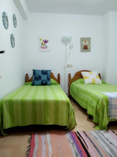 two beds in a room with green sheets at An'Ca' La Pura in Villanueva del Conde