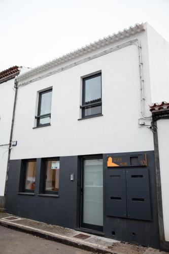 a white building with a black door and windows at Slope House in Lagoa
