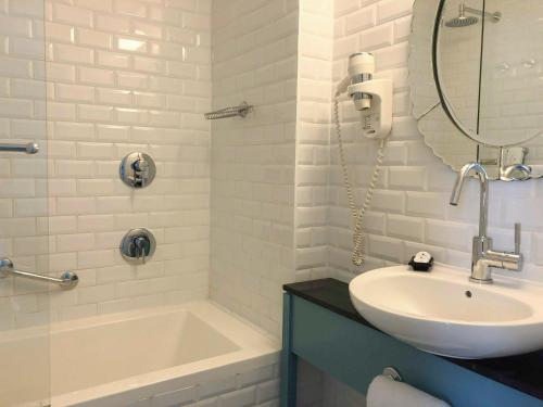bagno con lavandino, vasca e specchio di Center Chic Hotel - an Atlas Boutique Hotel a Tel Aviv