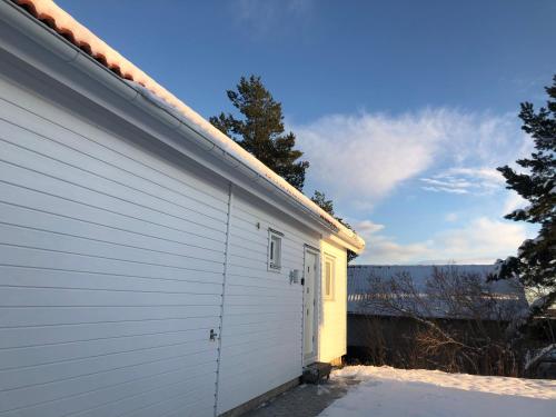 a white building next to a house in the snow at Great Stay Guest House Sandviken in Sandviken