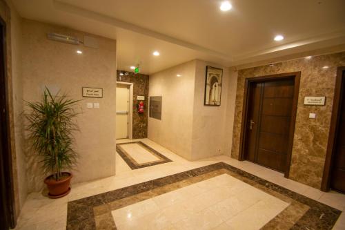Waha AL Mudaif Serviced Apartments في تبوك: ممر فيه باب وزرع الفخار