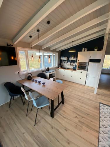a kitchen and dining room with a wooden table and chairs at Nátthagi Luxury Cottage in Snæfellsbær