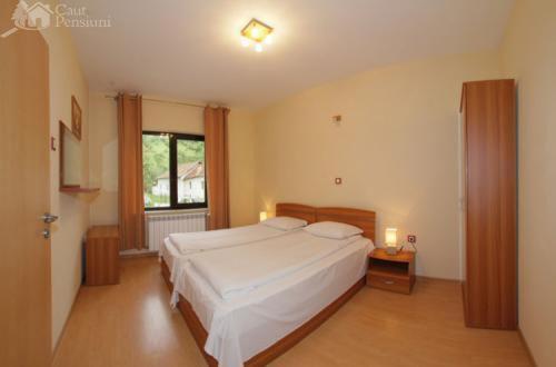 een slaapkamer met een groot wit bed en een raam bij Pension Camelia in Băile Herculane