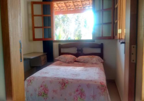 a small bedroom with a bed with a window at Chalé Boa Vista in São Thomé das Letras