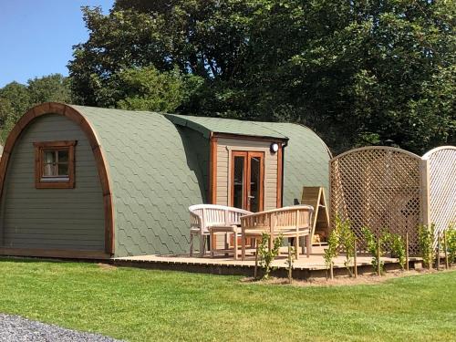 a small shed with a table and chairs in a yard at Brynteg Glamping in Llanallgo