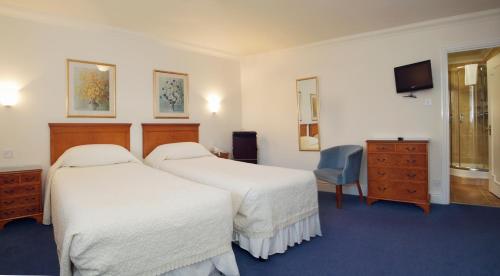 a hotel room with two beds and a tv at The Corbyn Apartments in Torquay